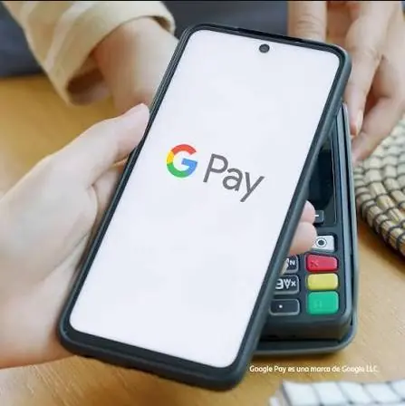 Teléfono con el logotipo de Google Pay junto a un terminal de pago